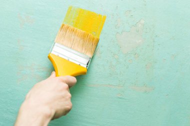 sarı bir fırça ile bir adamın elini duvara sarı boyar. Daire Tadilat kavramı