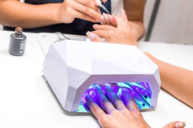 Güzellik salonunda manikür. Manikür ustası oje geçerlidir. İkinci el cihaz kurutulur