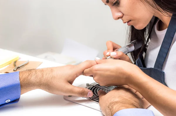 Young woman is doing a manicure to a man in a beauty salon. Concept man is a metrosexual. Copy space