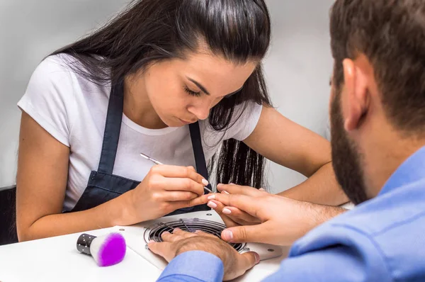 Young woman doing manicure to a man. Concept spa procedures and cosmetology for men.