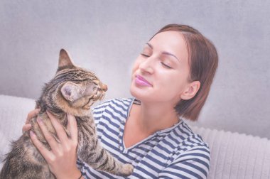 Genç kadın bir kedi onun kollarında tutar. Yakın çekim portre