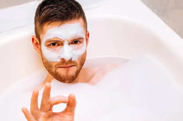 Genç Adam Bir Yüz Maskesi Ile Bir Köpük Banyo Yer — Stok fotoğraf