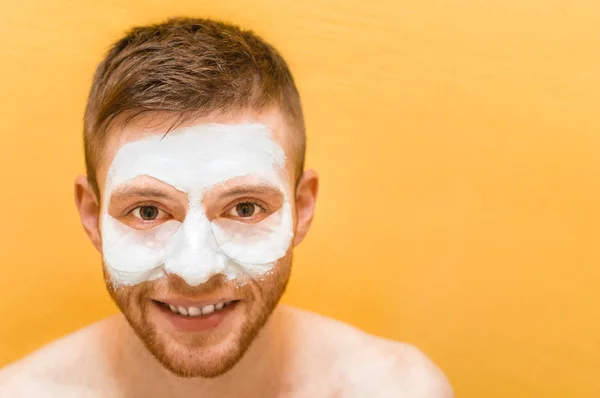 Young man with facial mask on a yellow background. Concept care for yourself for men.
