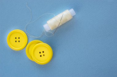 Üç sarı düğme ve mavi bir arka plan iş parçacığında bir makara.