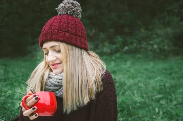 Young woman with a cup of coffee on nature. Concept autumn