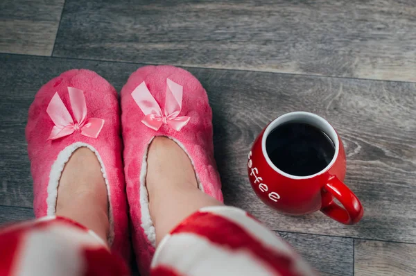 Feet in pink soft slippers and pajamas. Concept weekend.