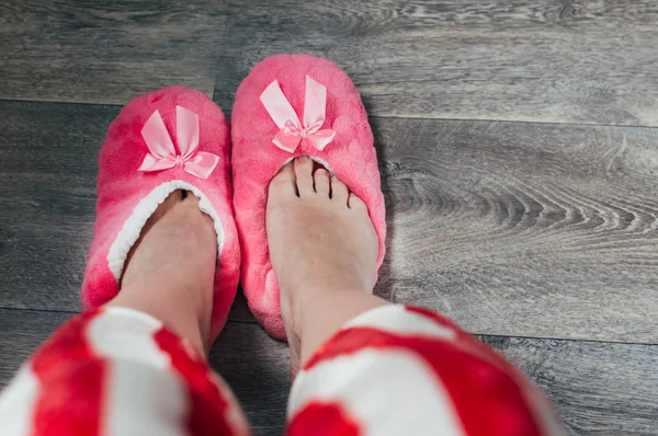Feet in pink soft slippers and pajamas. Concept rise in the morning.