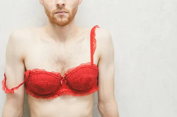 Young man in a red women's bra. 