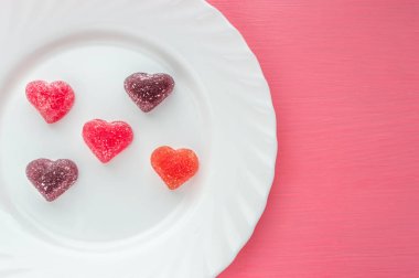 Marmelat pembe bir arka plan beyaz bir plaka üzerinde kalp şeklinde. Sevgililer günü kavramı.