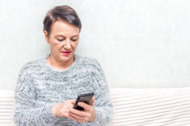 Kanepede otururken üst düzey Bayan ussing smartphone portresi