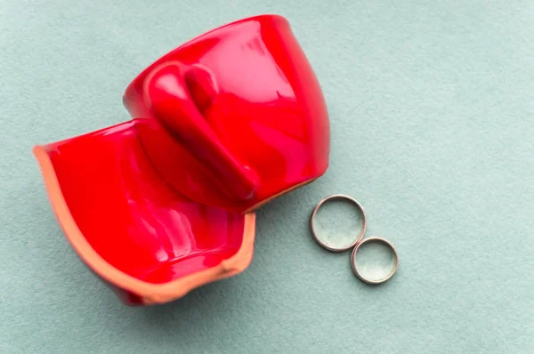Broken red cup and wedding rings. Concept divorce