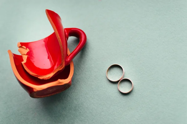 Broken red cup and wedding rings. Concept parting