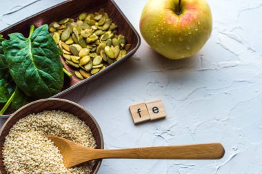 Spinach, pumpkin seeds, sesame, apple and one wood spoon on a white background. microelement FE. Close-up. clipart
