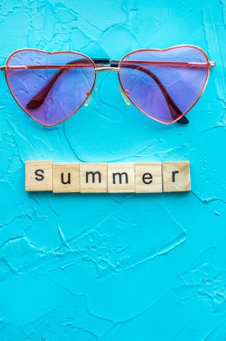 Pembe Kalp şeklinde güneş gözlüğü mavi bir arka plan üzerinde. Kavram yaz. Minimalizm. Dikey fotoğraf