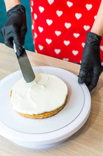 Pastelero pone crema en un pastel de esponja. Proceso de elaboración de pasteles — Foto de Stock