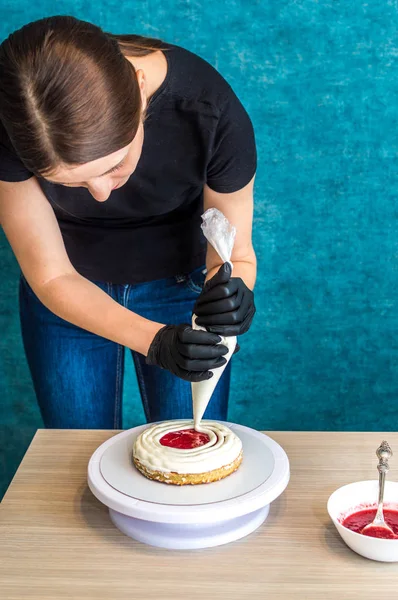 Confitero aplica la crema en el pastel de bizcocho. Proceso de elaboración de pasteles. Foto vertical — Foto de Stock
