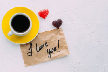 Sarı fincan kahve beyaz zemin üzerinde. Not seni seviyorum. Kopya alanı