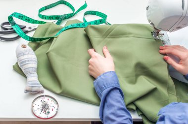 Dikiş Atölyesi. Genç bir kadın bir dikiş makinesi diker.