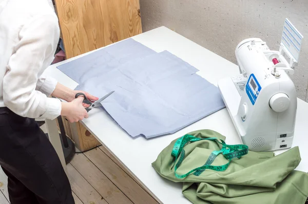Швея делает разрезание ткани на рабочем столе. Студия пошива. Производство одежды, процесс шитья — стоковое фото