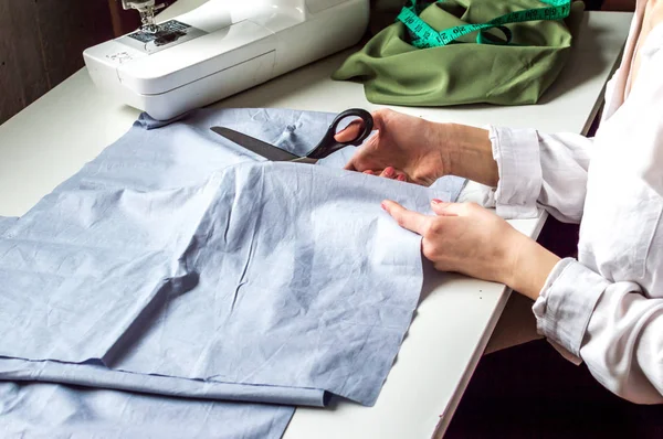 Couturière fait couper le tissu sur le bureau. Couture de studio. Production de vêtements, processus de couture — Photo