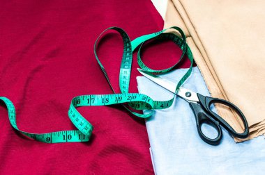 Dikiş aksesuarları. terzi kavramı. Çok renkli kumaşlar, mezura ve makas portre.