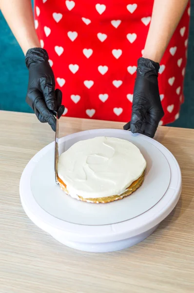 Pastelero pone crema en un pastel de esponja. Proceso de elaboración de pasteles. Foto vertical — Foto de Stock