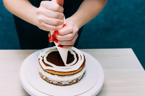 Ama de casa aplica la crema en el pastel pastel de galletas. Proceso de elaboración de pasteles. Foto vertical — Foto de Stock