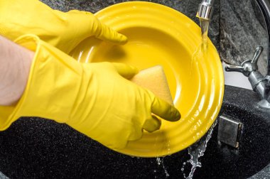 Dokunun yakın çekim altında bulaşık yıkama. Eldivenli elleri. Sarı plaka. Daire temizlik kavramını.