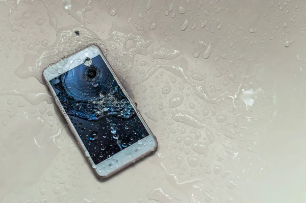 Phone dropped into the water. Telephone and water drops