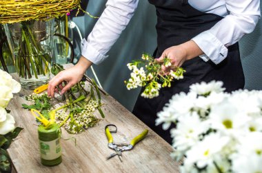 Bir buket çiçekçi çiçekçi dükkanı yakın çekim oluşturma süreci. Kadın elleri ve aracı