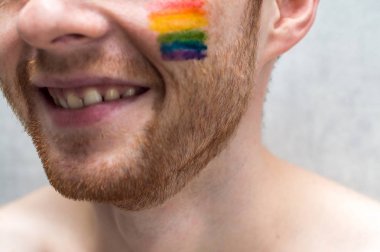 insanın yanağında gökkuşağı bayrağı. Kavram sembolü Lgbt