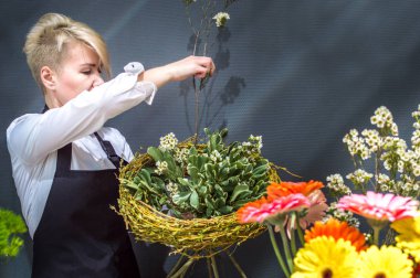 Çiçek dükkanında kadın çiçekçi bir buket çiçek toplar