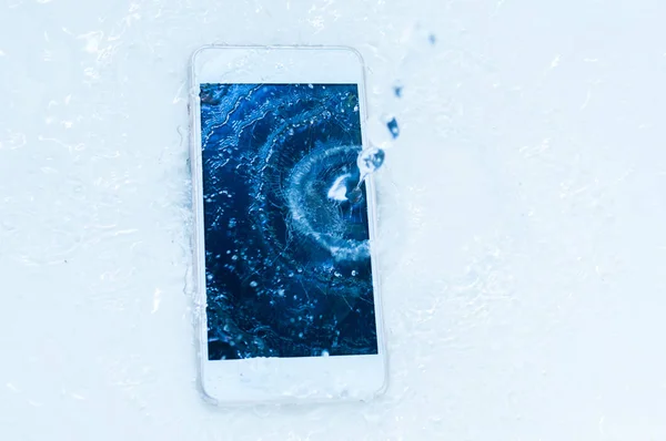 Phone dropped into the water. Telephone and water drops