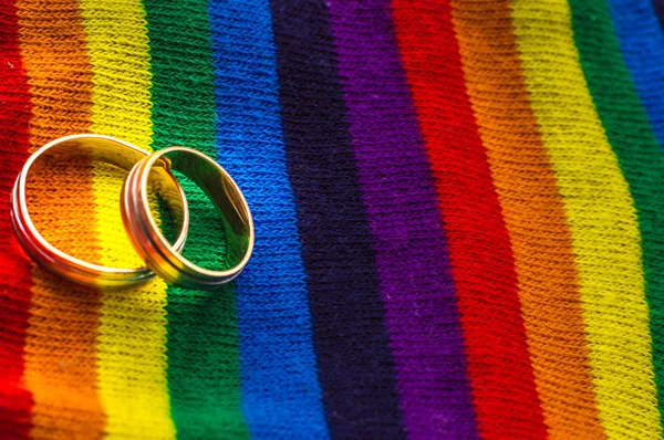 Dos anillos de boda en los colores de tela del arco iris. Concepto matrimonio entre personas del mismo sexo. Espacio Cope —  Fotos de Stock