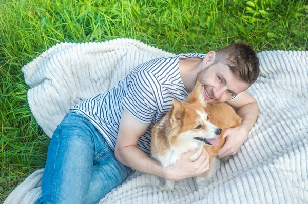 Proprietário está descansando na natureza com seu cão. homem abraça um cão em uma planície na grama — Fotografia de Stock