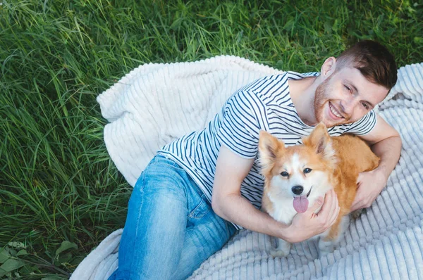 Щасливий усміхнений чоловік зі своїм собакою лежить на траві — стокове фото
