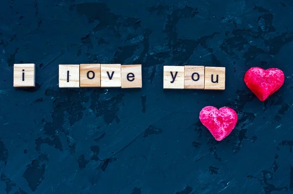 Inscripción Te amo y dos corazones se presenta en letras de madera sobre un fondo de madera oscura. Concepto de San Valentín. Febrero . — Foto de Stock