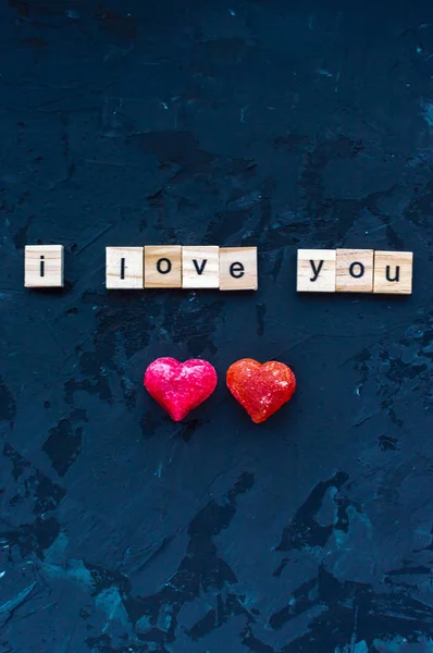 Inscripción Te amo y dos corazones se presenta en letras de madera sobre un fondo de madera oscura. Concepto de San Valentín. Febrero. Foto vertical — Foto de Stock