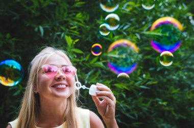 Genç bir kadın sokakta balon üfleyicisi üflüyor. Yakın plan portre. Mutluluk ve pozitif duygular kavramı