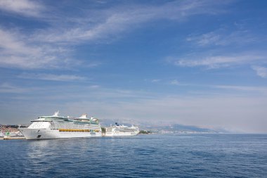 SPLIT, CROATIA, 08.15.2020: Cruise ships anchored near a picturesque coastal city with scenic views and a vibrant skyline, under a clear blue sky and tranquil seas.