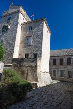 Günışığı kireçtaşı kulesi ve etrafındaki taş binalar Avrupa 'da tarihi bir avlu oluşturur. Yukarıda bayraklar dalgalanıyor, tuğla ve taş dokular geleneksel mimariyi vurguluyor, kaldırım taşları sonsuz cazibe ve karakter katıyor.