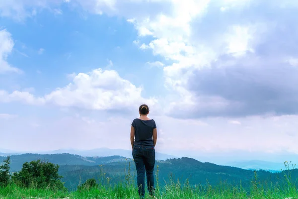Sırt çantası ile kadın yaz aylarında inanılmaz orman ve dağlara bakıyor, seyahat konsepti, metin için alan. Ormanda ve mavi gökyüzü ve tatilde bulutlar görünümü