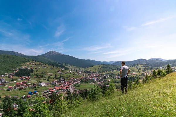 Adam dağdan dağlardaki köye bakar.