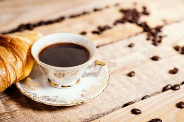 ahşap bir masa üzerinde lezzetli bir kruvasan ile lezzetli ve hoş kokulu kahve