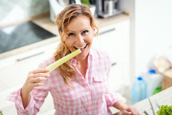 Wanita Tersenyum Memegang Dan Rasa Seledri Hijau Segar Dapur — Stok Foto