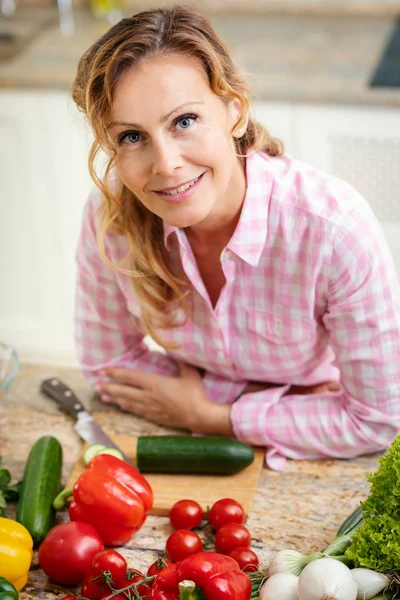 Muotokuva Hymyilevä Nainen Nojaa Pöytää Vasten Vihanneksia Keittiössä — kuvapankkivalokuva