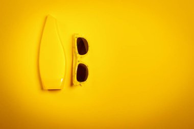 güneş gözlüğü ve güneş kremi ile minimalist sarı tatil arka plan