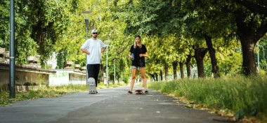 Erkek ve kadın kaykaylar ile ayakta ve sokakta binmek hazırlanıyor