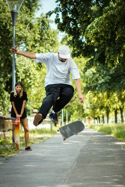 Chico Realiza Truco Skate Chica Sienta Mira Día Verano —  Fotos de Stock