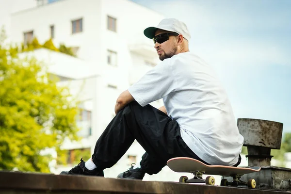 シャツを着た男はスケート ボードに座っていると夏の日の周りに見える — ストック写真